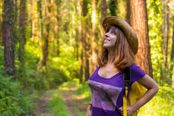 Traveler woman smiling with hat and looking at the forest pines, hiker lifestyle concept, copy and...