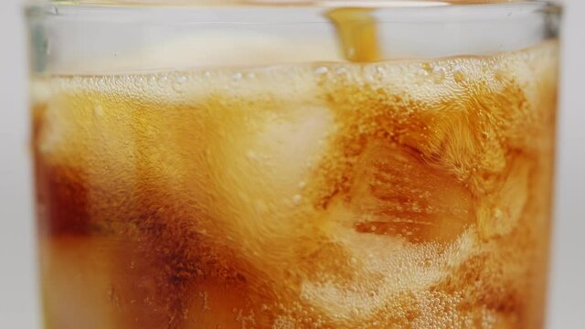 Slow motion 4K. A sweet  cold soft drink is poured into a glass filled with ice cubes. refreshing delicious drink Thirst quenching drink.