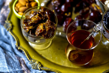 A table with Turkish tea with lale, oriental sweets, rahad delight, a mix of various nuts using copper dishes and bright fabrics.