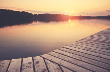 Fototapeta na wymiar Wooden pier at Lipie Lake at sunset, selective focus, color toning applied, Strzelce Krajenskie, Poland.