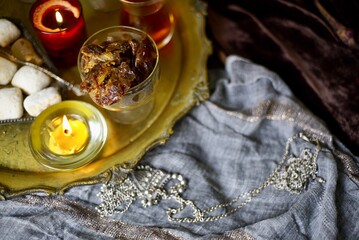 A table with Turkish tea with lale, oriental sweets, rahad delight, a mix of various nuts using copper dishes and bright fabrics.