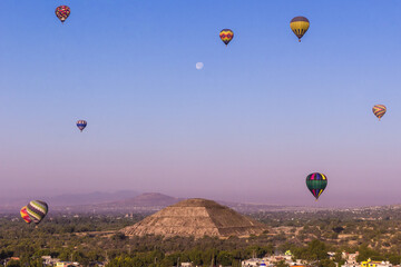 Globos aerostáticos volando cerca del templo del sol de Teotihuacan en México, amanecer con la luna, azul colorido