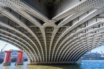 The underside of Blackfriars Railway Bridge over the River Thames  with some of the remaining columns from the old bridge - obrazy, fototapety, plakaty