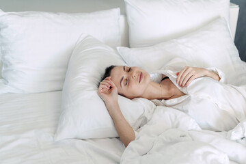 Young woman sleeping on white bedclothes in bedroom