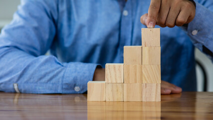 Businessman protect wooden block fall to planning and strategy in risk to business Alternative and...
