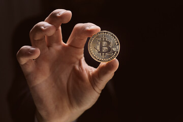 Fototapeta premium Close up man hand holding golden Bitcoin over black background