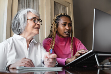Multiracial young and senior people using computer laptop indoor at home - Multi generational people working inside office - Focus on african girl face