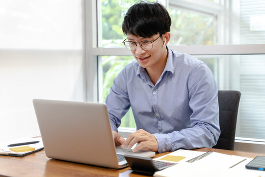 Asian Male Business Person Using Headphone And Laptop Video Conference Meeting Online Work At Home..