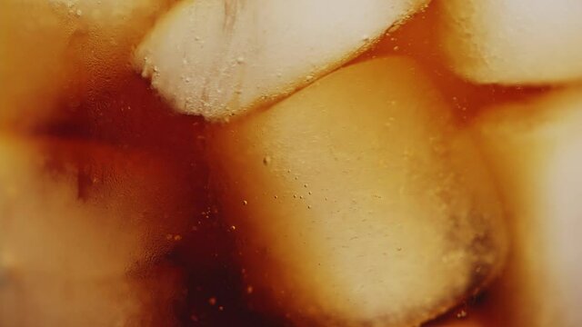Slow motion 4K. A sweet  cold soft drink is poured into a glass filled with ice cubes. refreshing delicious drink Thirst quenching drink.