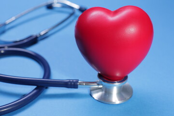 Red heart shape and medical stethoscope on blue background