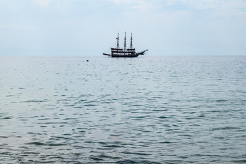 Silhouette of a three-masted vintage ship on the sea horizon. Beautiful seascape with copy space