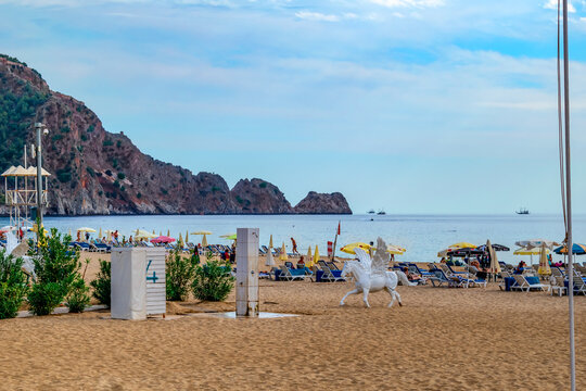 Alanya, Turkey - October 23, 2020: White plastic sculpture of pegasus on Damlatas beach in Alanya. Horse with wings among the yellow sand against the background of sun loungers with umbrellas