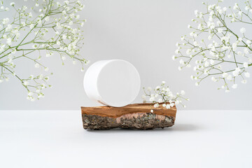Round blank plastic cosmetic jar for advertising on rough wooden podium and white gypsophila...