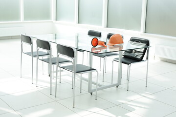 Construction helmet and loudspeaker on glass table in office space