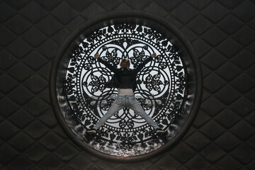 A beautiful girl stands with her back in a stained glass window. Sunbeams in a stained glass window. Play of light and shadow.