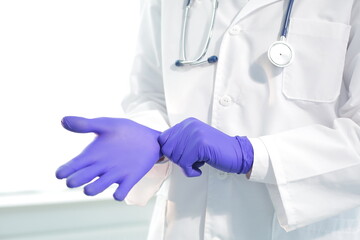 Doctor with a medical stethoscope in a medical gown and protective gloves is filling a syringe with a vaccine