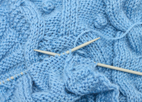 Blue knitted fabric and knitting needles 