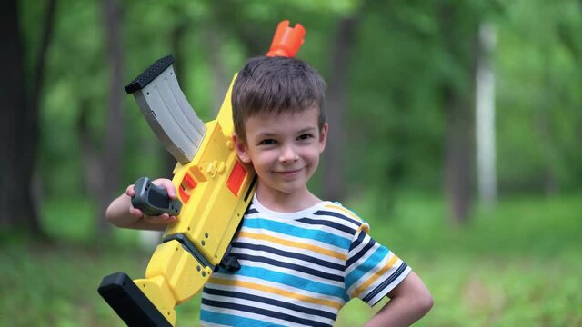 Portrait boy with large toy weapons outdoors.