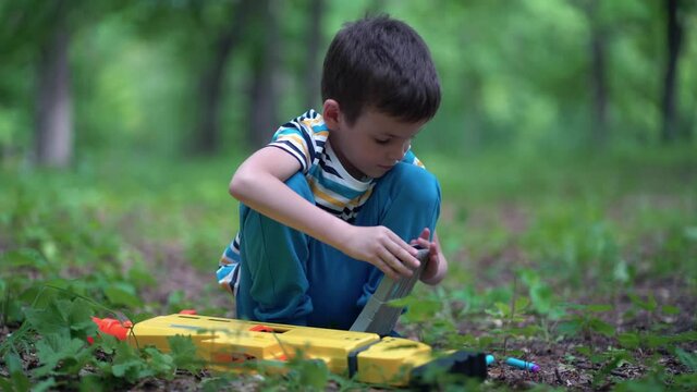 A boy loads a clip with cartridges from a toy gun