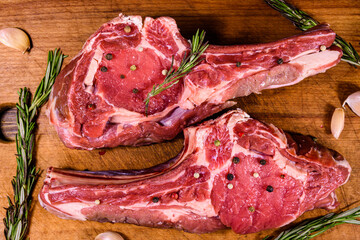 Raw ribeye steak, spices and rosemary on cutting board. Top view