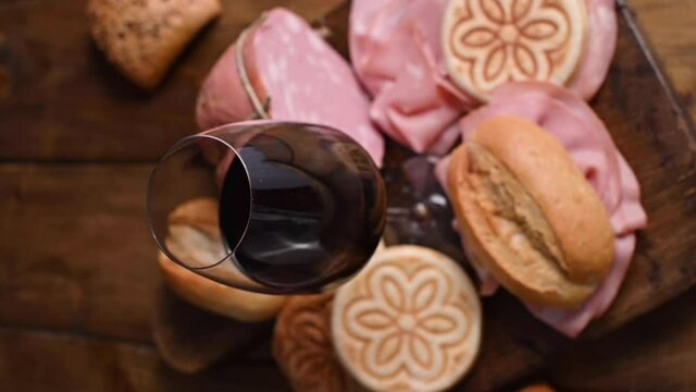 Red wine in a glass. Traditional pre-dinner snack in italy with wine, tojeteli baked goods, mortadella sandwiches. Food and drink of Emilia Romagna. High quality FullHD footage. Vertical video