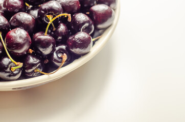 Closeup on fresh and ripe sweet cherries on a white ceramic plate