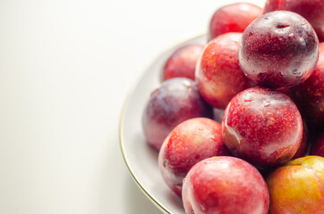 Closeup on fresh and ripe plums on a white ceramic plate