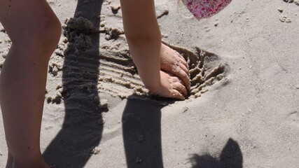 Closeup of toddler hands dig wet sand to make pit on beach. Leisure games with sea sand in summer sunny day. Sandcastle build activity kids play