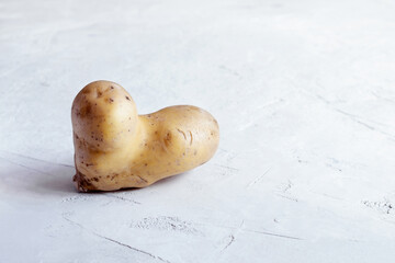 Ugly potatoes in the shape of a heart on a gray concrete background. Horizontal orientation