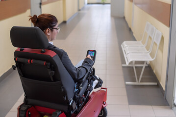 Fototapeta na wymiar Caucasian woman in electric wheelchair in hospital corridor.