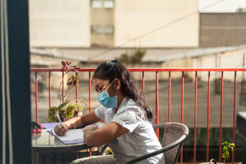 Guatemalan girl doing homework at home while quarantining of epidemic coronavirus.