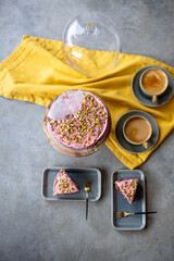 Nut strawberry cheesecake and coffee drinks on the concrete background with yellow tablecloth, view from above. Cake pieces on a plates ready to eat