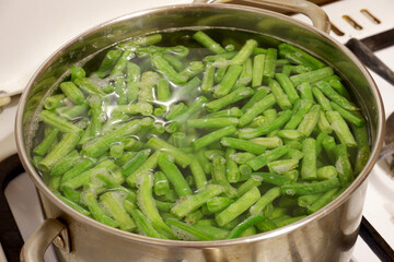 Green beans are cooked in an iron saucepan