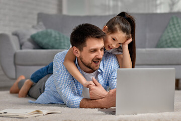 little child girl and handsome father using laptop