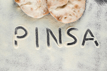 Dough and flour with text pinsa on black background. Pinsa romana and scrocchiarella gourmet italian cuisine. Traditional dish in italy.