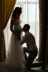 the groom kisses the belly of the pregnant bride. full length dark silhouette
