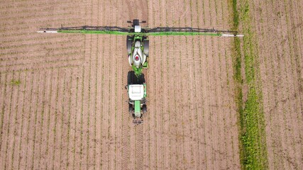 Traktor mit Spritze bringt Pflanzenschutz oder Flüssigdünger auf ein Acker aus, Luftbild © keBu.Medien