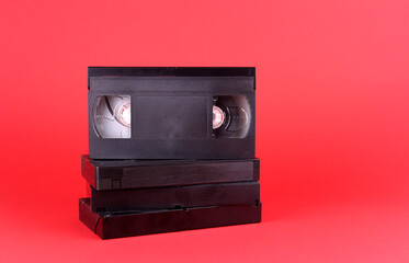 Black videotapes on a red background. Old technologies for video storage - obrazy, fototapety, plakaty