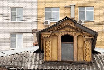 Attic of a residential wooden house view from the outside against the background of a modern multi-storey residential building
