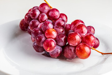 Beautiful close-up of cluster of red grapes (inks) on table. Fresh, raw and water drops.