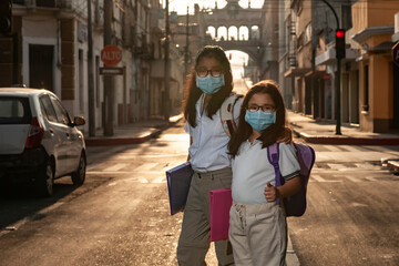 Girls with a medical mask and uniform walk to school with uniforms and books.