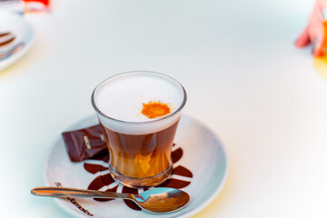cortado de café con leche natural con azucarillo y cucharita en mesa de bar
