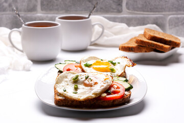 Sandwiches with egg, tomatoes, cucumbers, a plate of bread, two cups of tea.