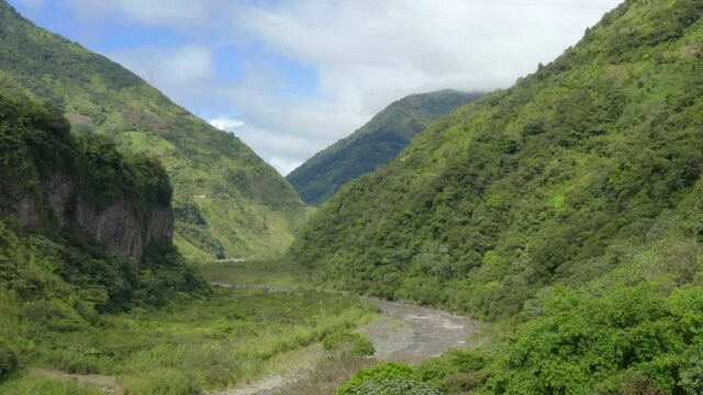 Aerial view of a large river in a sup-tropical mountainous area that is going down a large green colored canyon