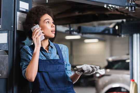 worried young african american mechanic speaking on cellphone in garage - Powered by Adobe