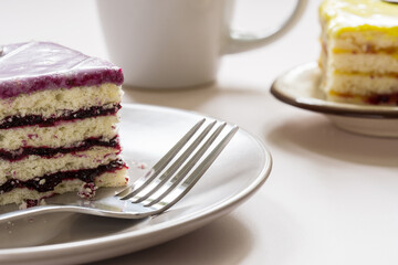 Berry cake on a plate with a fork. Lemon cake and white cup on the background.
