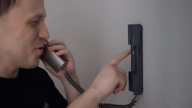 The man answers the intercom call, opens the door, close-up