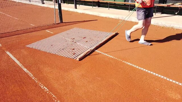 Tennis court maintenance. Leveling the surface of the site. Smoothing with a net after renewing the soil surface. Preparing for the new playing season, training and competition.