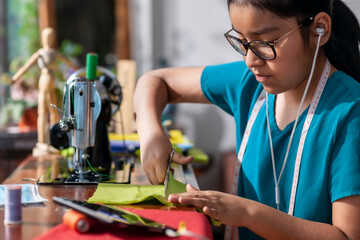Girl listening to music while cutting cloth on a sewing machine.