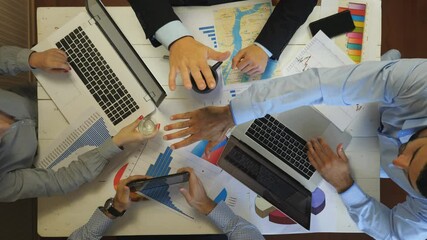 Male and female hands of colleagues putting their arms in centre and raising them up at office. Group of managers stacking hands together one by one in unity. Support and motivation concept. Top view